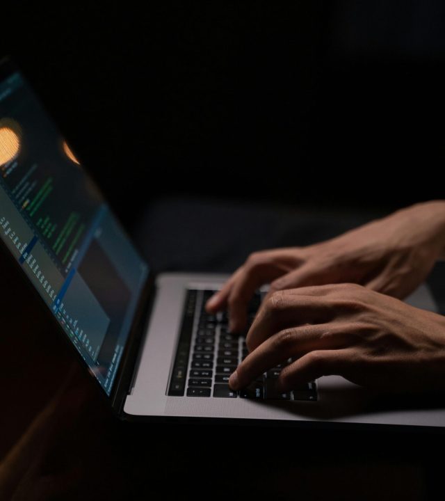 pexels-photo-5496464-5496464 Hands typing code on a laptop keyboard in a dark room, capturing the essence of late-night programming.