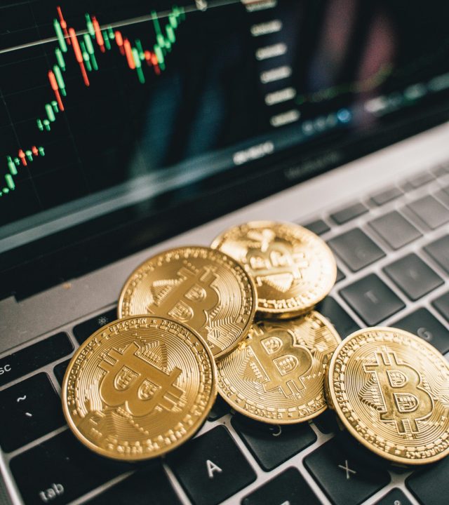 pexels-photo-6770845-6770845 Close-up of gold Bitcoin coins on a laptop keyboard with a stock chart, symbolizing cryptocurrency market analysis.